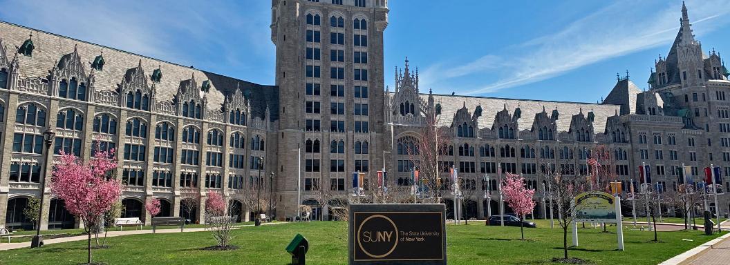 SUNY Plaza in the sunlight with stone SUNY logo sign in front.