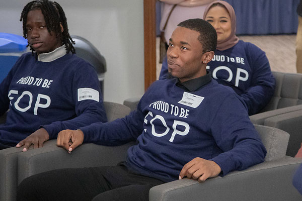 SUNY Educational Opportunity Program students wearing Proud To Be EOP shirts sit in clb chairs listening to someone speak.