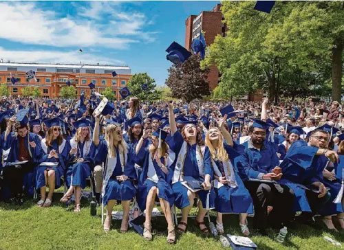 SUNY New Paltz graduates throw their graduation caps in the air after their graduation ceremony.